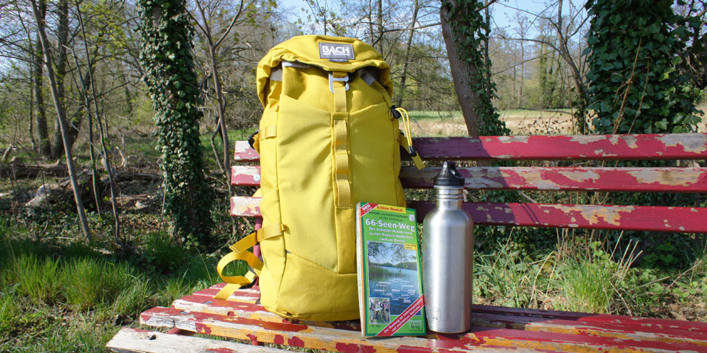 A backpack, a map and a waterbottle on a old bench at the 66-lakes-trail.