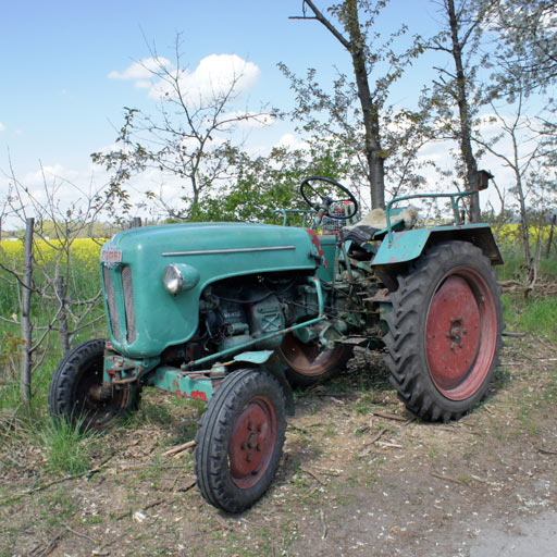 An old green tractor standing next to a field.