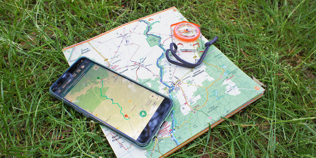 A smartphone with a hiking app, a compass and a map.