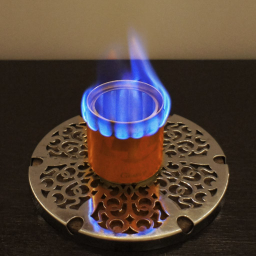 A handmade alcohol stove burning with a low flame.