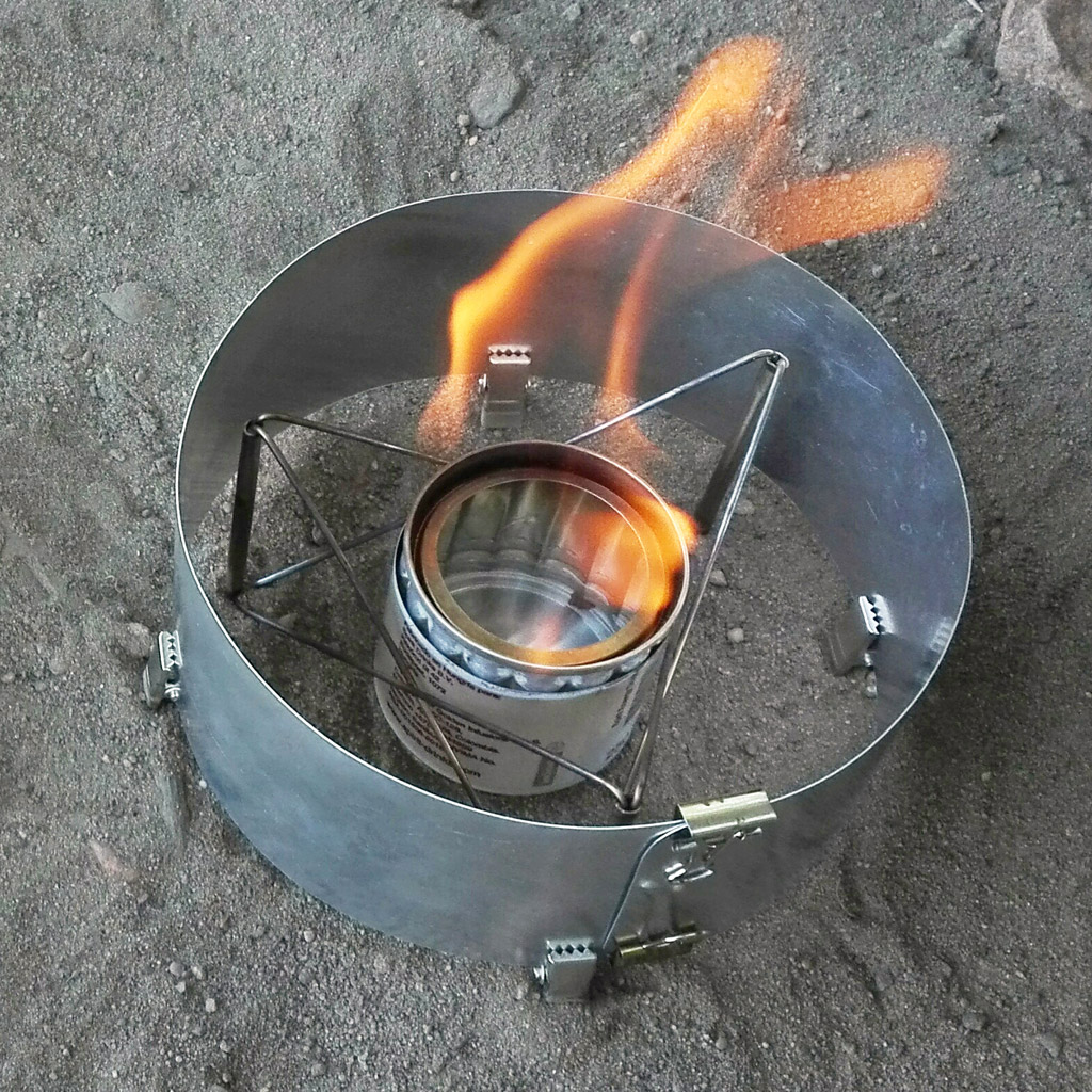 Burning alcohol stove with handmade pot stand and DIY windscreen.
