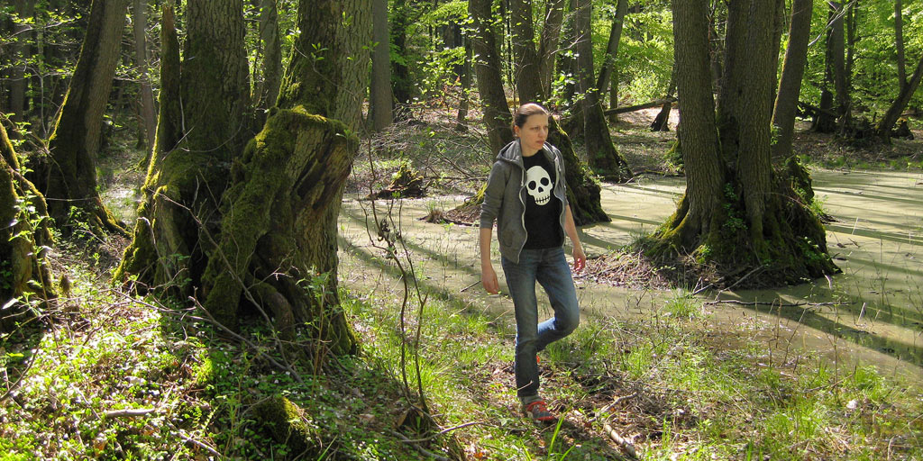 Woman walking through a swamp wearing a skull T-shirt.