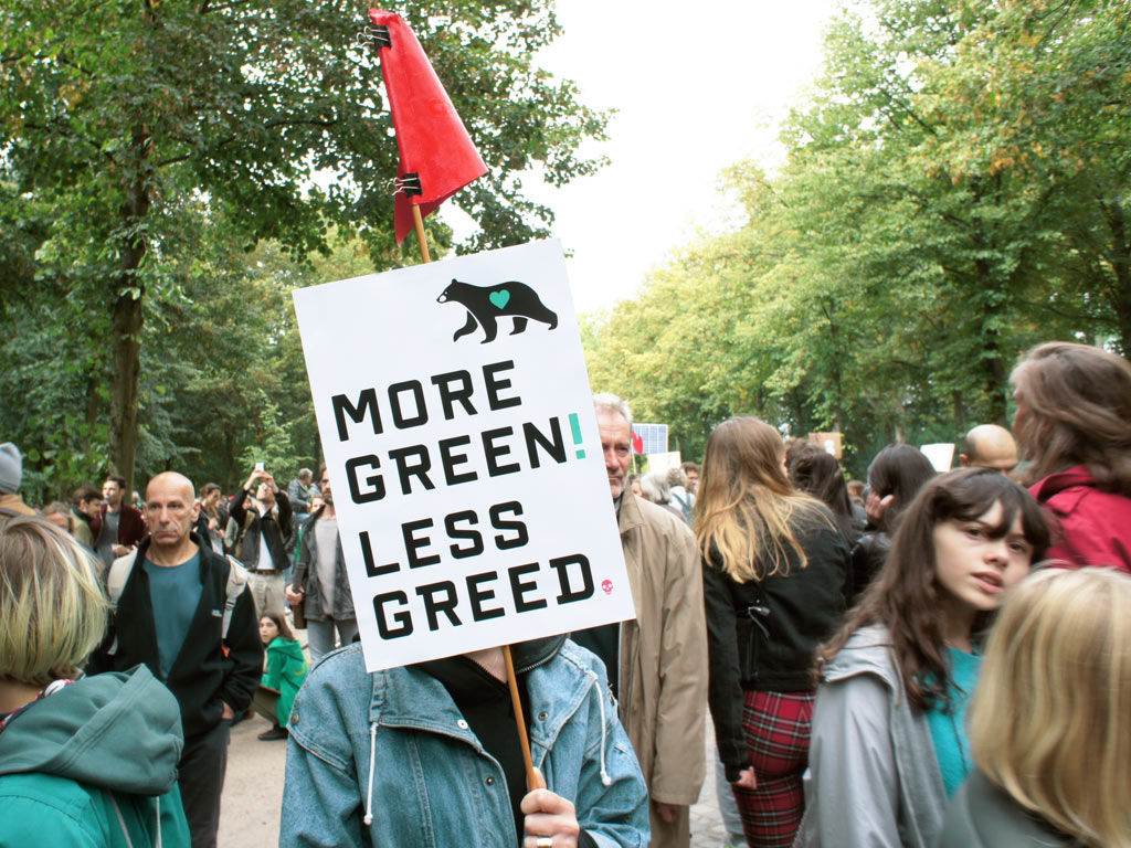 protest sign: more green, less greed