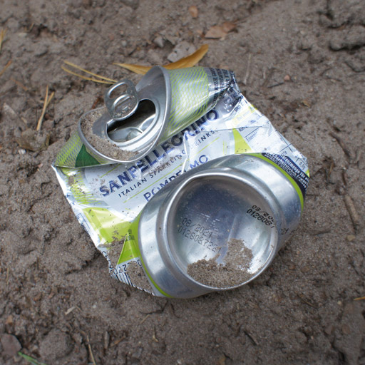 Crumpled can laying on the ground.